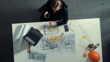 Üst düzey inşaat mühendisi yapışkan notlar yazıyor ve dizüstü bilgisayara bakıyor. Hava görüntüleme mimarı bilgisayar analizi yaparken toplantı masasında oturuyor ve bina yapısını hesaplıyor. Hizalama.