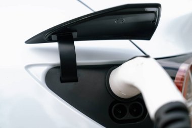 Elektrikli araç portuna bağlı EV şarj prizi kolu şarj istasyonundan şarj oluyor. Modern tasarlanmış EV araba ve daha iyi bir gelecek konsepti için temiz enerji sürdürülebilirliği. Eşzamanlama