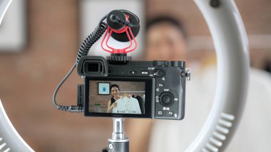 Arka görünüm, kamera ekranında kadın nüfuzunu gizler. Video görüntüleme, video görüntüleme, giysi, sosyal medya ya da blog. Canlı yayın için canlı stüdyo ışıklandırması olan kız canlı yayın pazarlama kaydı