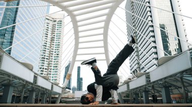 Genç Asyalı hippi şehir merkezinde insanların etrafında ayak izlerini gösteriyor. Şık bir sokak dansçısı B-boy ya da serbest dans eder. Açık hava sporu 2024. Break dans. Yumuşak bir şekilde..