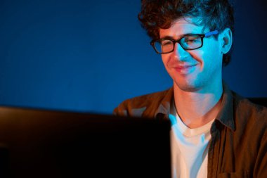 Neon Light Modern Ofis 'te yaratıcı bir başlangıç projesi için bilgisayara odaklanan gülümseyen genç iş adamı. Düşünüyorum da, pazarlama ağı yaratıcıdan pazar kanalı tasarım konseptine çevrimiçi planlama. Toplayıcı.