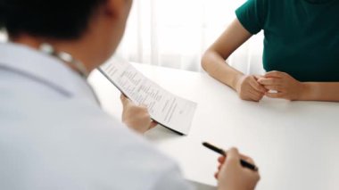 Klinikteki ya da hastane ofisindeki doktor randevusuna katılan hasta, tıbbi tedavi seçeneklerini tartışıyor ve muayene sonuçlarını ya da hastalıkla ilgili tıbbi kayıtları açıklıyor. Ağır çekim. Katı.