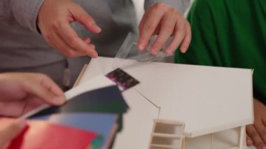 Mimari ekipman kullanarak yavaş çekim ev tasarımcısı bir plan çizerken, iç mimari tasarımcı da müşterilerin talebine göre renk örneklerinden uygun renkler seçiyor. Değiştirilmiş