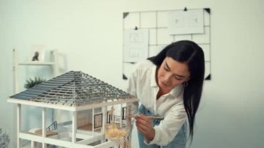 Genç, güzel ve zeki mühendisin yakın çekimleri modern ofiste duvarında taslak olan kalem kullanarak ev modelini ölçmeye odaklanıyor. Yaratıcı yaşam ve tasarım konsepti. Tertemiz..