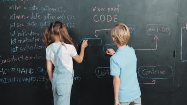 Beyaz kız mühendislik komut veya kodlama ile karatahta yazma, BTMM teknoloji sınıfında yazılan programlama sistemi ve erkek başparmak gösterirken kameraya bakmak için geri dönüş. Etkinlik.