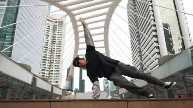 Genç Asyalı hippi şehir merkezinde insanların etrafında ayak izlerini gösteriyor. Şık bir sokak dansçısı B-boy ya da serbest dans eder. Açık hava sporu 2024. Break dans. Yumuşak bir şekilde..