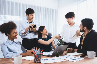 Çeşitli iş arkadaşları başarıyı şirket işyerindeki el sıkışma ve takım çalışmasıyla kutluyor. Çok kültürlü, mutlu profesyonellerden oluşan bir ekip ofiste tokalaşarak birlik oldular. Uyum