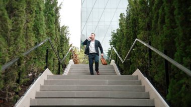 Kafkas işadamı merdivenlerden çıkıp akıllı telefon kullanarak müdürü arıyor. Yöneticinin pazarlama ekibinden bahsetmesi ve merdivenleri çıkarken telefonla finansal strateji planlaması. Urbane.