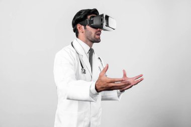 Tıbbi teoriyi açıklarken VR gözlük ve laboratuvar önlüğü takan beyaz, zeki bir doktor. Profesyonel doktor tıbbi verileri analiz ederken görsel gerçeklik kulaklıkları kullanarak metaevreni bağlıyor. Sapma.