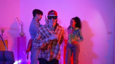 Mutlu hipster stüdyoda neon ışıklı kameraya bakarken süslü gözlük takıyor. Komik mutlu dans takımı hip hop kafiyesine ya da modern pop müziğiyle beyaz sanatçıya taşınıyor. Mutluluk.