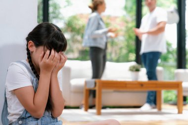 Stresli ve mutsuz genç kız, arka planda ebeveynleri tartışırken yüzünü kapatıyor. Evde aile içi şiddet ve travmatik çocukluk depresyona dönüşür. Eşzamanlama