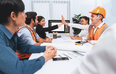 Çeşitli inşaat mühendisi ve müvekkil grupları, mimari proje üzerinde başarılı bir anlaşma yaptıktan, inşaat planını gözden geçirdikten ve toplantı masasında plan oluşturduktan sonra kutlama ve beşlik çakışma yaptılar.