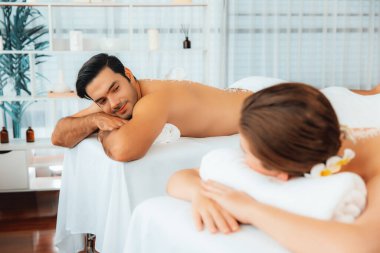 Lüks spa salonlarında sıcak mum ışığında cilt bakımı gören mutlu çift müşterisi. Sağlık kaplıcasında güzellik tedavisiyle tuz temizliği. Sessiz.