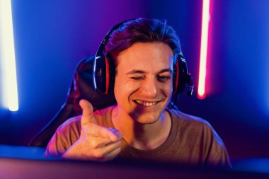 Kazanmak için çevrimiçi oyun oynayan akıllı flama makinesinin sunucu kanalı, neon ışıklı odada seçilen takım yarışması için izleyicilerle birlikte canlı yayında canlı yayında kulaklık takıyor. Bireysel.