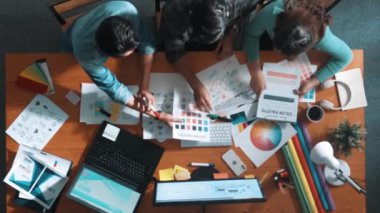 Tasarımcı fikirleri yazarken proje yöneticisinin yukarıdan aşağıya bakan görüntüsü. Akıllı iş adamları logo tasarımı fikrini açıklarken tasarımcılar palete bakarken temayı seçiyorlar. Sempozyum.