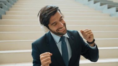 Kulaklık takarken müzik dinleyen ve eğlenen zeki iş adamlarına yakın çekim. Proje yöneticisi gülümserken iyi haberler alıyor, terfi alıyor, satışları artırıyor. Rahatlatıcı adam müzikten hoşlanır. Sevinçli..