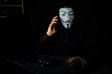 Beyaz gülümseyen isimsiz suçlu maskesi kurbana sesleniyor, kişisel bilgileri hacklemeye ikna ediyor, veri sunucu sistemindeki bilgisayar korsanlarının kullandığı şifreleme programını paylaşıyor. Tahmin et..