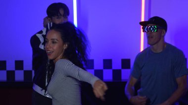 Gündelik gömlekli, gözlüklü, neon ışıkla dans eden farklı insanlar. Gece kulübünde dans ederken kameraya bakıp sokak dansı yapan çok kültürlü break dansçı. Mutluluk.