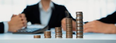 Büyüyen madeni para yığını iş yatırımını ve ekonomik büyümeyi simgeliyor. Finansal hedefe ulaşmak ve maksimum kâr sağlamak için finansal planlama yapan iş adamları. Kurnaz.