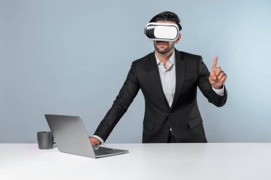 Akıllı iş adamı teknoloji yeniliklerini kullanarak veri analizini seçerken dizüstü bilgisayarla masada duruyor. Sanal gerçeklik gözlüğü ve sanal gerçeklik gözlüğü kullanan yetenekli Kafkas proje yöneticisi. Sapma.