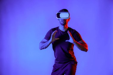 Kafkasyalı bir adam metaevrene girmek için VR kulaklık takarken basketbol oynuyor ya da neon ışıklı bir dünya canlandırıyor. Sanal gerçeklik dünyasında dururken spor yapan ya da egzersiz yapan sporcu. Sapma.