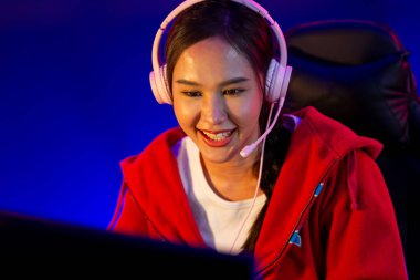 Portre sunucusu güzel Asyalı kız flamasının çevrimiçi oyun oynaması kulaklık takması pastel renkli konuşmalar izleyici medyası ile çevrimiçi. Esport yetenekli takım oyuncuları neon mavi odada. Taktik.