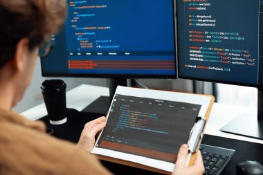 IT geliştiricisi kodlama uygulama ekranlarında ekranlarda ekranlarla birlikte belge kağıdı yazılımında kodlama okuyor, güncellenmiş program yazılım bilgi sürüm kavramını yaratıyor. Toplayıcı.