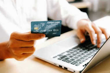 Genç adam, laptop bilgisayar başvurusu ya da web sitesinde online alışveriş yapmak için kredi kartı kullanıyor. E-ticaret ve online alışveriş konsepti. uds