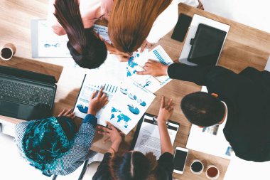 Modern ofisteki iş adamları ve iş kadınlarıyla grup toplantısındaki iş adamlarının en üst düzey görüşü, masada dizüstü bilgisayar, kahve ve belge ile. Kurumsal şirketler uds