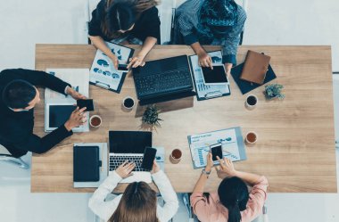 Modern ofisteki iş adamları ve iş kadınlarıyla grup toplantısındaki iş adamlarının en üst düzey görüşü, masada dizüstü bilgisayar, kahve ve belge ile. Kurumsal şirketler uds