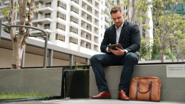 Kafkas iş adamları yeşil şehirde otururken tablet üzerinde çalışıyorlar. Uzman yönetici iş ekibiyle çalışırken finansal veri analizi yapmak ve aramak için tablet kullanıyor. Urbane.