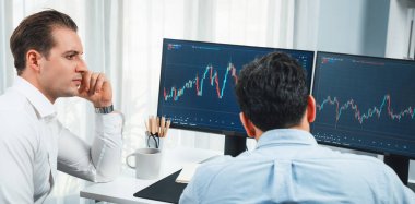 Borsa simsarları panorama manzarasında iki ekranla karşılaştırma yaparak, monitörde analiz yaparak borsa borsasını tartışıyorlar. İş yerindeki finansal teknoloji krizi kavramı. Satılabilir.