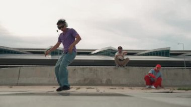 Bir grup Asyalı break dansçı, çok kültürlü arkadaş desteği ve hareketli hip hop müziğiyle sokak dansı yaptılar. Çekici yakışıklı hippi sokak dansında break dansçı. Açık hava sporu 2024. Yumuşak bir şekilde..
