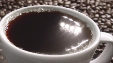 Kahve çekirdeğini yaklaştır ve kahve çekirdeği yığınıyla birlikte sıcak espresso 'ya bırak. Makro taze kavrulmuş fasulye aromatik dumanla bardağa düşüyor. Ağır çekim. Organik kahve tohumu kavramı. Geliştirilebilir.