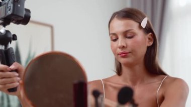 Sosyal medya için güzellik ve kozmetik video içeriği hazırlayan genç bir kadın. Güzellik blogcusu kameraya gülümserken seyircilere ve takipçilere güzellik bakımını gösteriyor. Düzenle