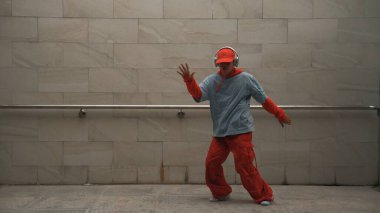 Yakışıklı koreograf gri arka planda sokak dansı yapıyor. Genç ve çekici dansçı çocuk şık kıyafetler giyerken gösteri yapıyor. Hareketli bir adım. Uzayı kopyala Açık hava sporu 2024. Yumuşak bir şekilde..