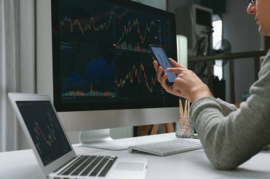 Akıllı borsa yatırımcıları ekranda akıllı telefon ile piyasa borsasını işaret ederek dizüstü bilgisayarın yanı sıra en yüksek dinamik yatırım oranını göstererek, modern işyerindeki veri planlamasına odaklanıyorlar. Bireysel.