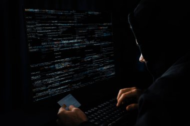 Suçlu anonim erkek, gece vakti mavi neon ışıklı odada sunucu sürücüsü ile şifre kırma programı kodlamak için kişisel bilgi veritabanının kredi kartına yaklaşıyor. Tahmin et..
