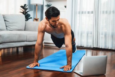 Atletik ve sporcu adam, evdeki fiziğe ve sağlıklı spor yaşam tarzına uygun vücut egzersizi sırasında spor minderinde şınav çekiyor. Gaiety evde egzersiz eğitimi.