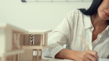 Modern ofisteki ev modelini planla ölçmek için kalem işaretleme noktası ve cetvel kullanmaya odaklanan genç ve güzel mimar mühendisinin yakın çekimi. Yaratıcı tasarım ve mimar konsepti. Tertemiz..