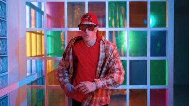 Serbest stil tişört giyerken sokak müziği çalan mutlu hipster. Gece kulübünde neon ışıkla dururken çekici break dansçı dans ve hareketli hareketler yapıyor. Mutluluk.