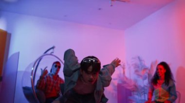 Çok kültürlü bir arkadaş kürsüde otururken Asyalı yetenekli bir dansçı modern müziğe geçiyor. Profesyonel dansçı, hipster takımı tezahürat yaparken ve desteklerken enerjik adımlar atıyor. Mutluluk.