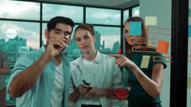 Mutlu iş adamları cam duvarı işaret ederken kendilerine güveniyorlar. İş adamlarından oluşan bir grup, şeffaf yönetim kurulunda iş fikri, strateji ve planlama ile ayakta duruyor. İzleme