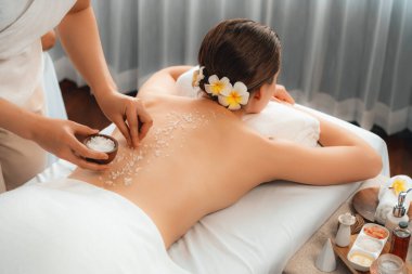 Lüks spa salonlarında sıcak mum ışığında cilt bakımı yaptıran kadın müşteri. Sağlık Spa vücut fırçasında tuz temizleme güzellik tedavisi. Sessiz.
