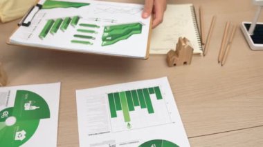 Şirketin gelecekteki EG 'si için yeşil enerji grafiği kullanımına danışmanlık ve analiz yapan iş ekibi. Yel değirmeni modeli, masadaki temiz enerji ve ev bloğu sembolize edilmiş eko evi kullanarak temsil ediliyor. Tanımlama.