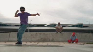 Bir grup Asyalı break dansçı, çok kültürlü arkadaş desteği ve hareketli hip hop müziğiyle sokak dansı yaptılar. Çekici yakışıklı hippi sokak dansında break dansçı. Açık hava sporu 2024. Yumuşak bir şekilde..