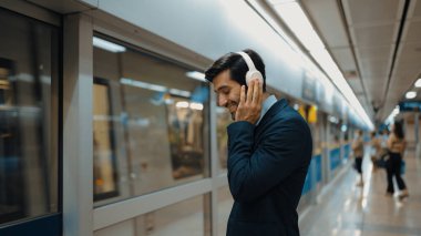 Proje yöneticisi tren istasyonunda şarkı seçmek için cep telefonu tutarken kulaklık takıyor. Zeki iş adamı bulanık bir geçmişi olan treni beklerken rahatlatıcı müzik dinliyor. Sevinçli..