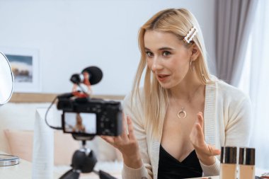 Sosyal medya için güzellik ve kozmetik video içeriği hazırlayan genç bir kadın. Güzellik blogcusu kameraya gülümserken seyircilere ve takipçilere güzellik bakımını gösteriyor. Blithe