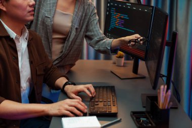 Bilgi teknolojisi geliştiricileri modern ofisteki neon ışık odasında verileri çevrimiçi olarak çalıştıran akıllı web sitesi geliştirme kodlayıcı sistemine işaret ediyorlar. İnfobahn.