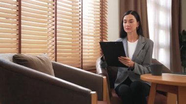 Mutlu ve gülümseyen kadın psikolog psikiyatri ofisinde ya da terapi odasında pano tutuyor. Arkadaş canlısı ve profesyonel ruh sağlığı danışmanı ya da terapisti. Blithe